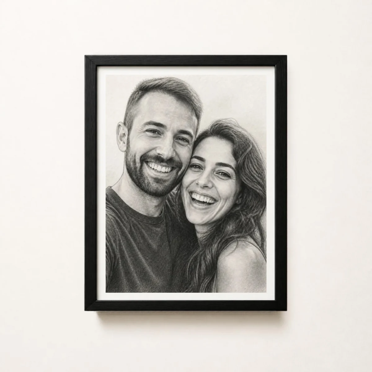 Pencil sketch portrait of a smiling couple in a black wood frame on a white wall